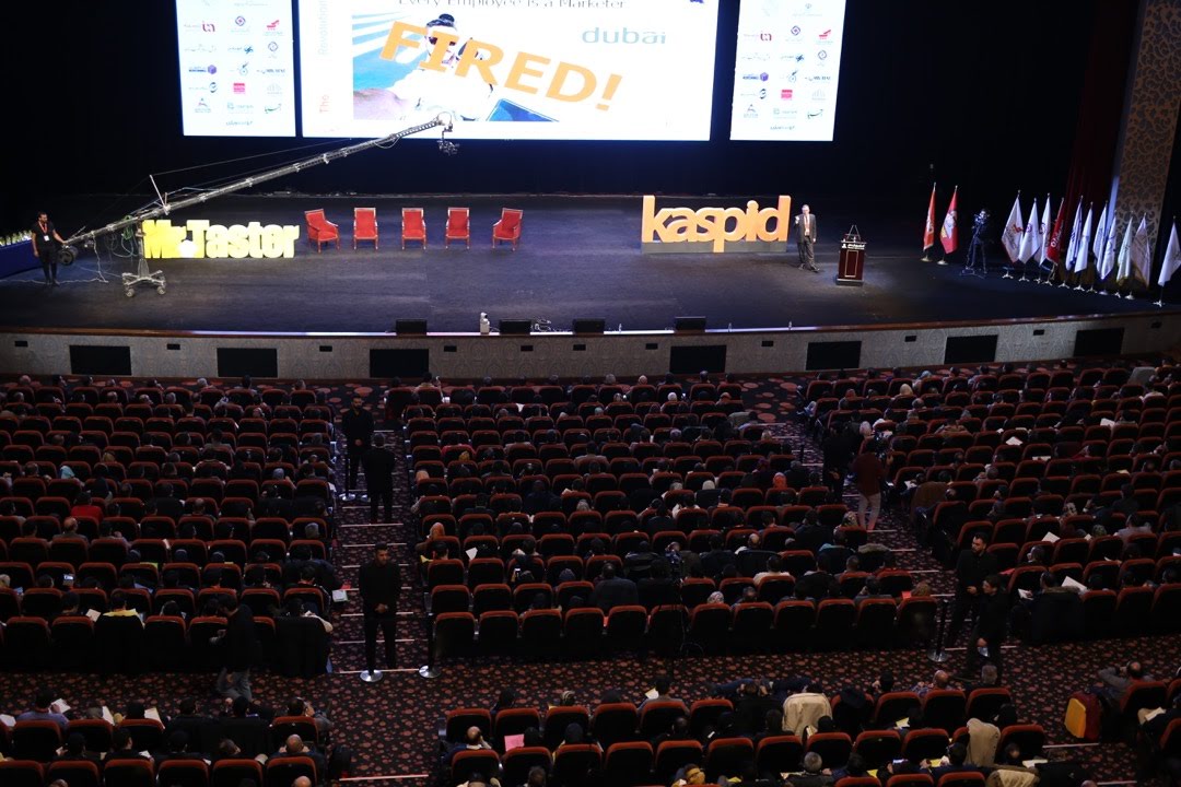 Conference audience facing a speaker on a large stage